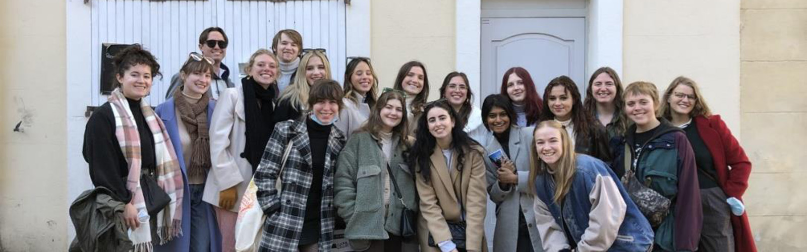 The cohort of students are gathered outside for a photo. They are close together and smiling at the camera.