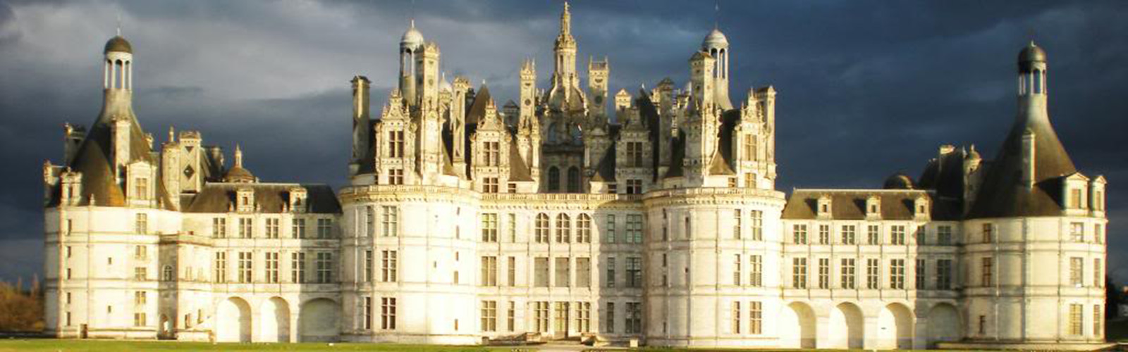 Expansive building in Tours. It has symmectrical windows and archways across the building, along with cylindrical pieces on the ends. The architecture near the top is very detailed.