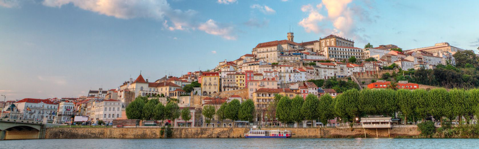 Old red-roofed buildings cover a hill along a river.
