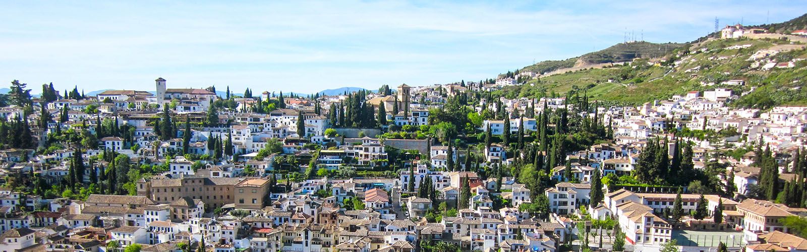 An aerial view of white, closely-packed buildings covering a hillside.
