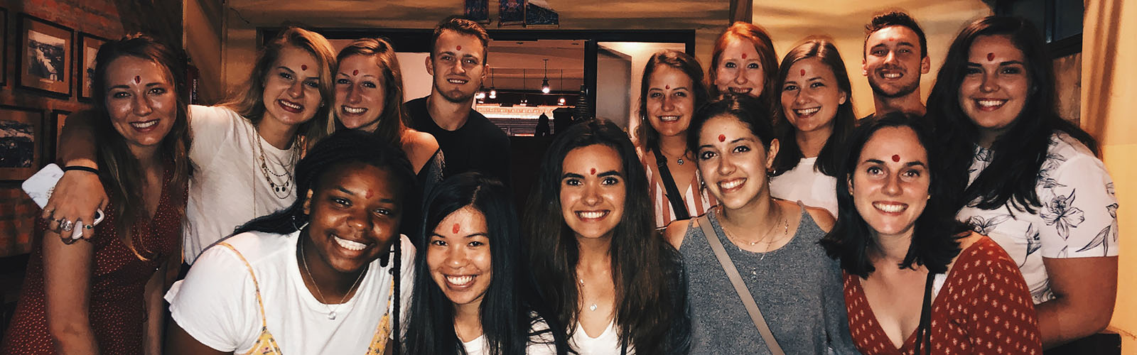 A group of students stand inside a building smiling. 