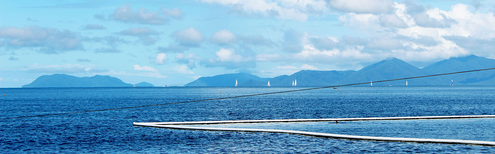 An expansive view of the ocean, with a mountain range in the background.