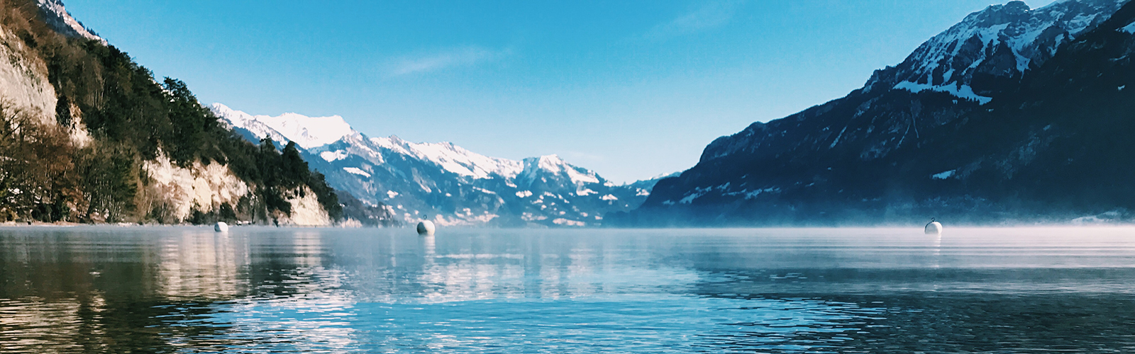 A calm lake surrounded by snowy mountains.