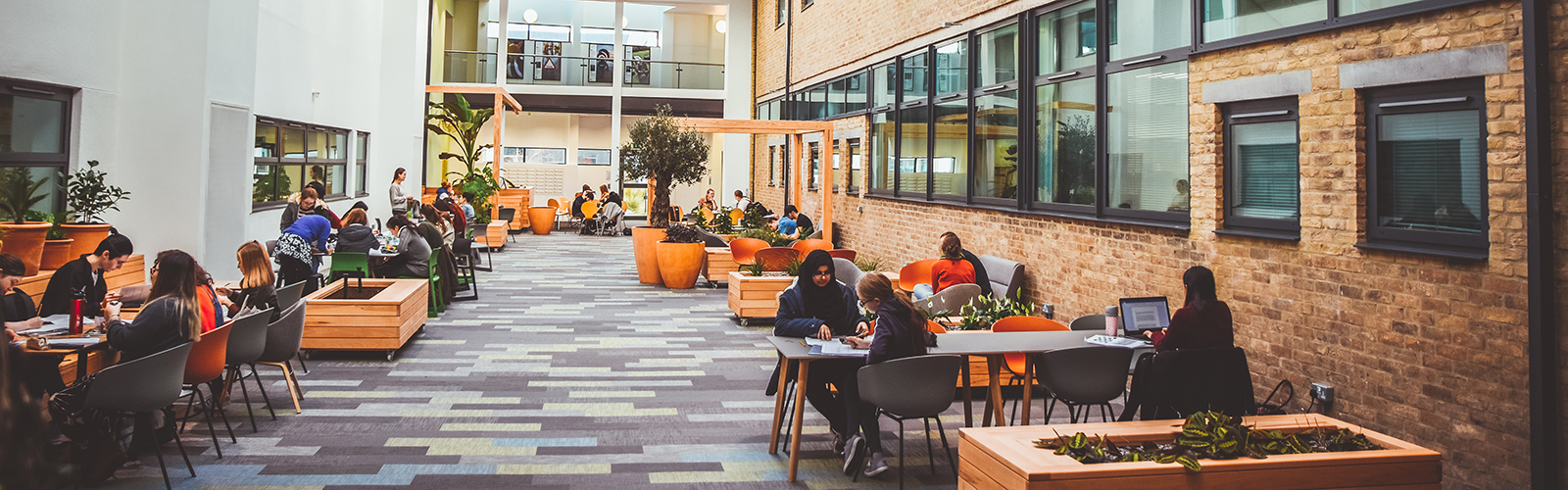 Common area in one of the university buildings. Students are sitting around tables and studying.