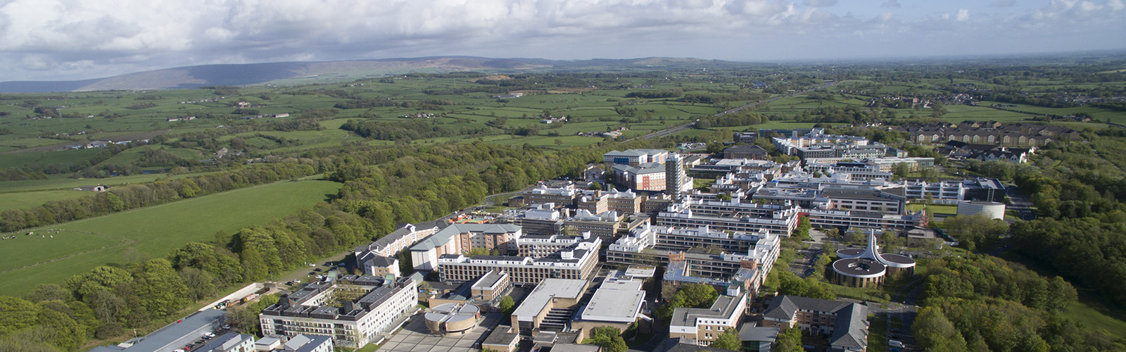 Drone shot of the University of Lancaster campus. The campus is closed off and surrounded by trees and fields. 