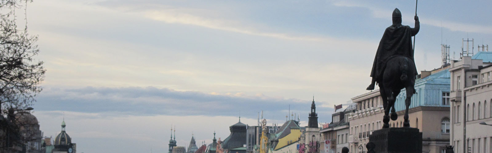 View of the top of Prague's buildings with an iconic statue of a soldier on a horse in the foreground.
