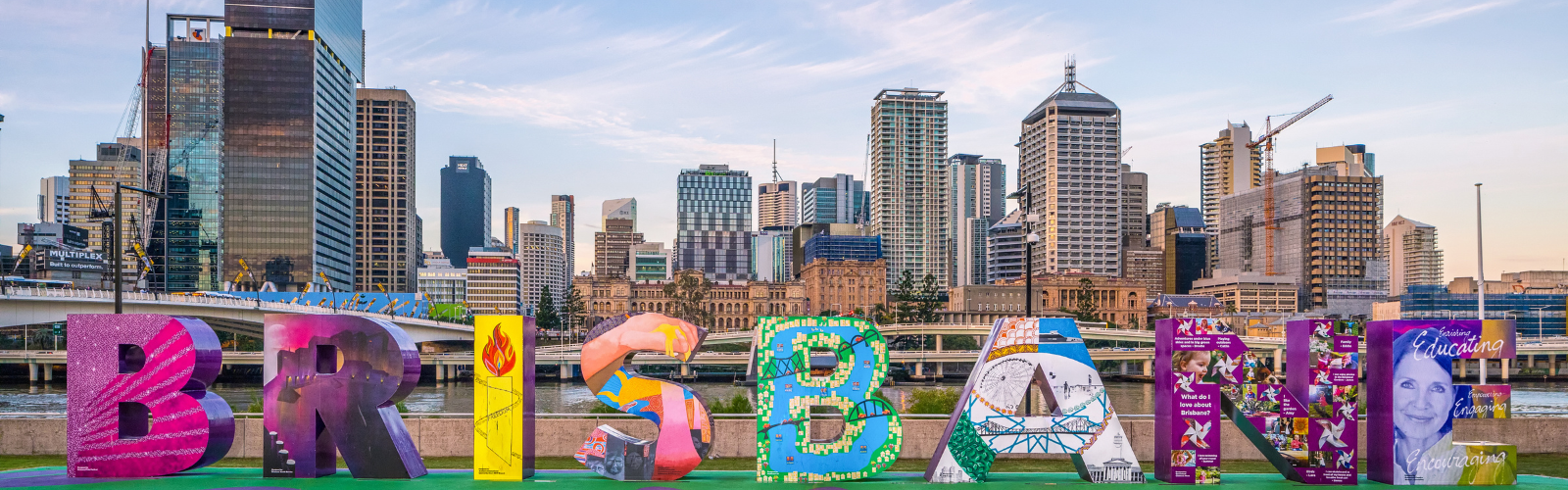 A colorful Brisbane sign with skyscrapers visible behind it.