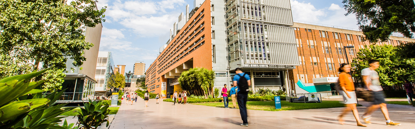 University campus with modern buildings and green spaces. Students are walking to and from their classes.