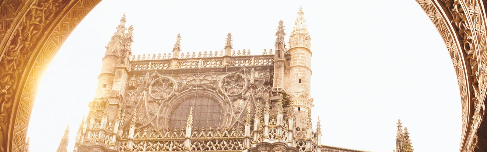 A detailed facade of Seville's cathedral, viewed through an archway.