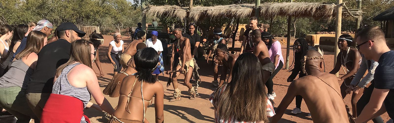 Students are engaged in a dance circle with local community members.