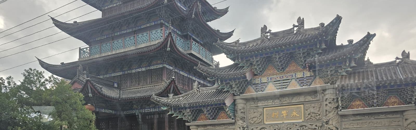 A brown building with slanted roofs and intricate colored details throughout the walls. 