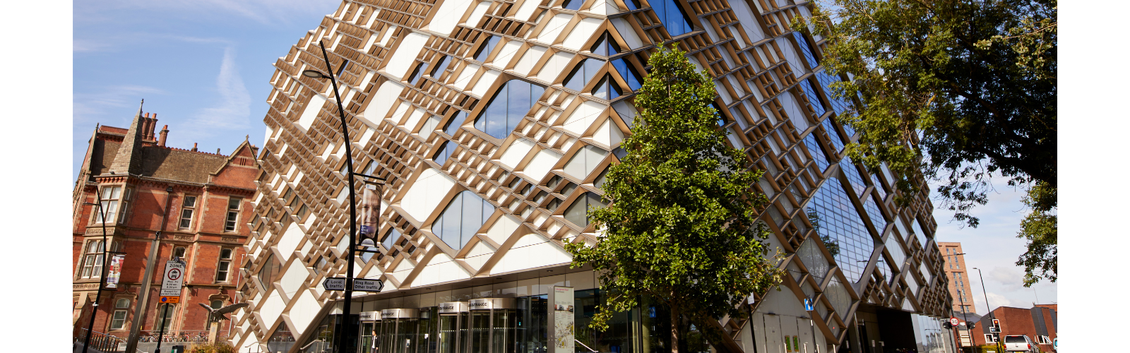 Exterior of a university building, highlighting the modern architecture with greenery surrounding the building.