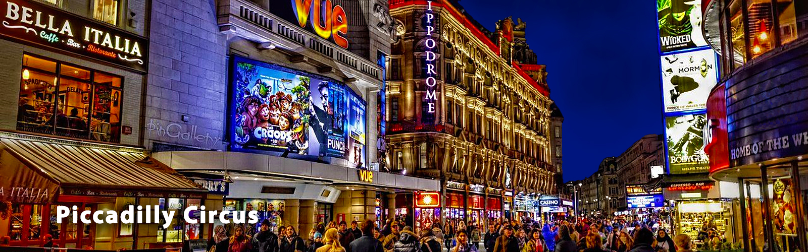 Street view of Piccadilly Circus lit up at night, along with some of the West-End theatre scene. People are crowding the streets.