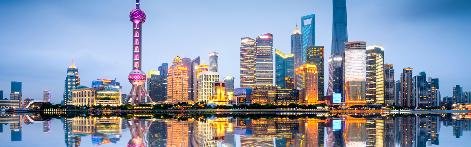 View of the Shanghai skyline from the water, highlighting the contemporary architecture. The city is lit up and vibrant.