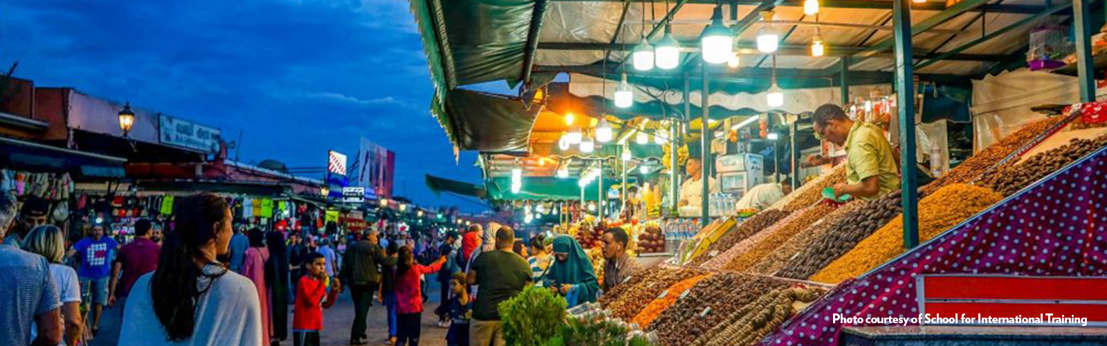 A busy market lined with shops, stalls, and carts.