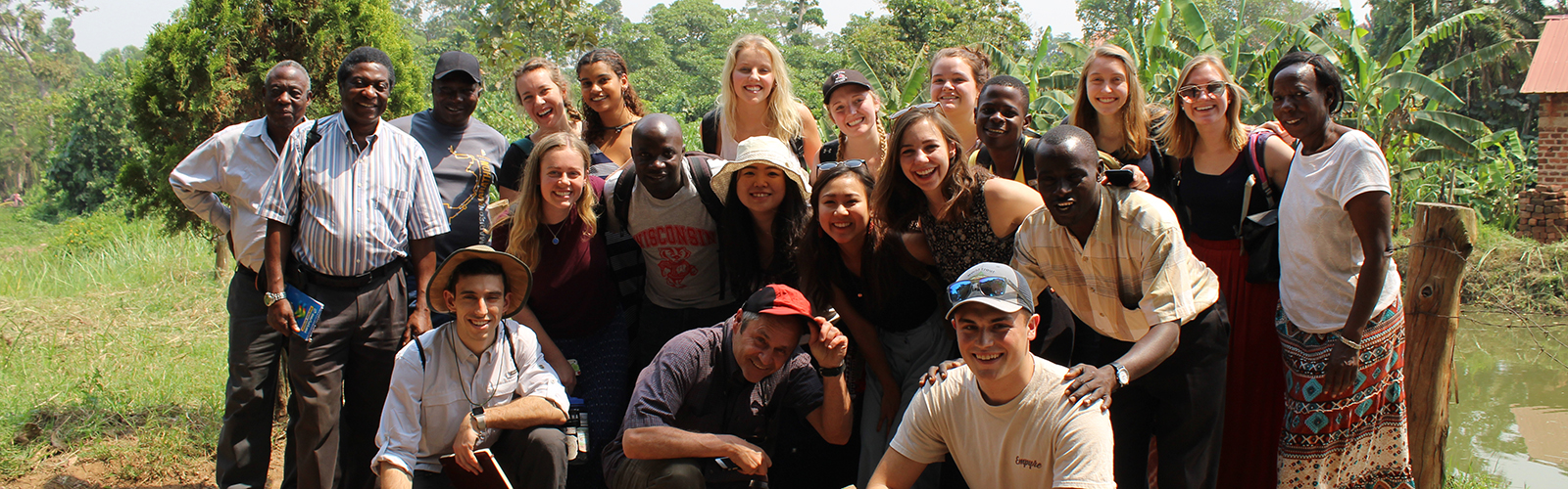 Program participants and other individuals posed in three rows outside of a farm.